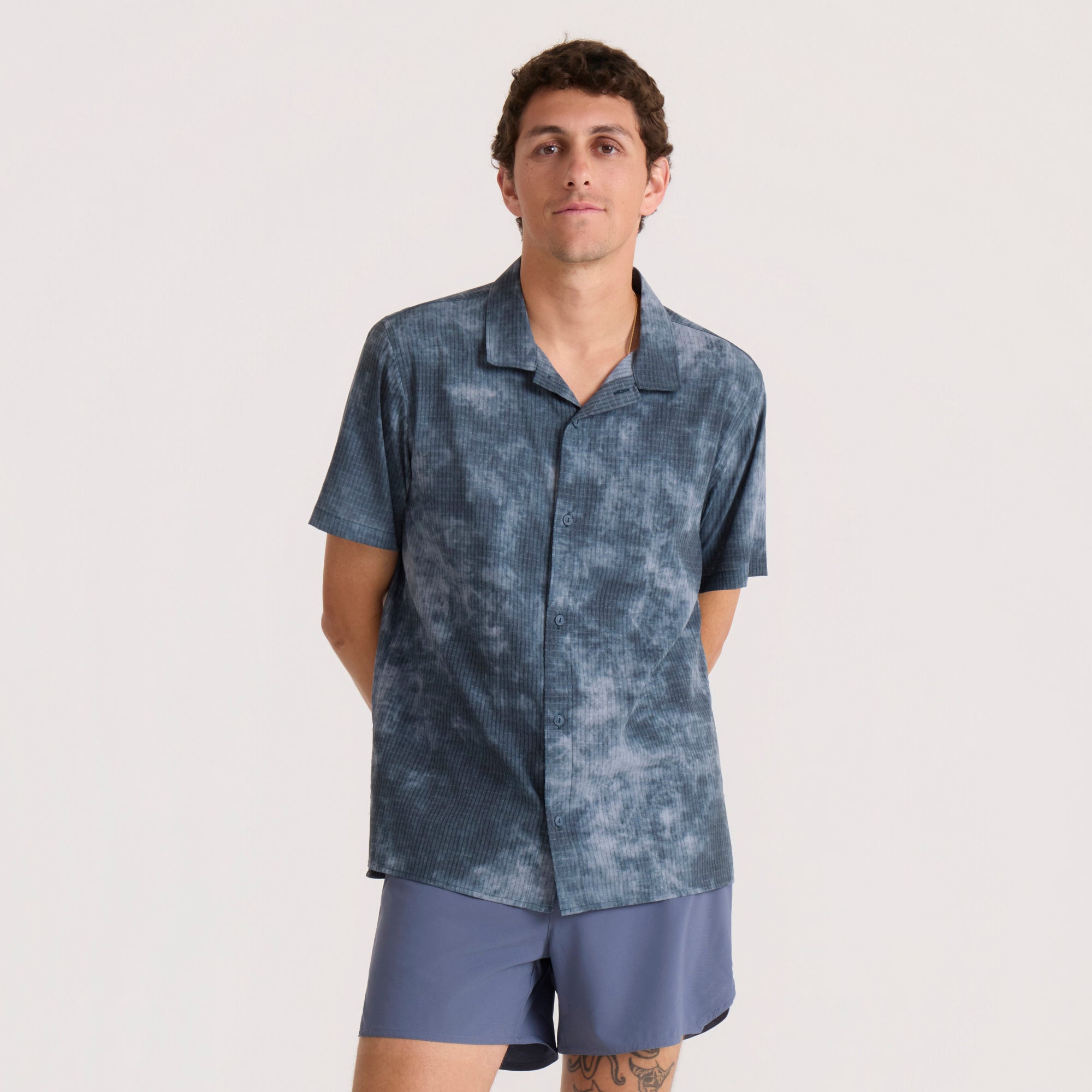 Dark slate textured short sleeve button up shirt on model paired with blue shorts against neutral background