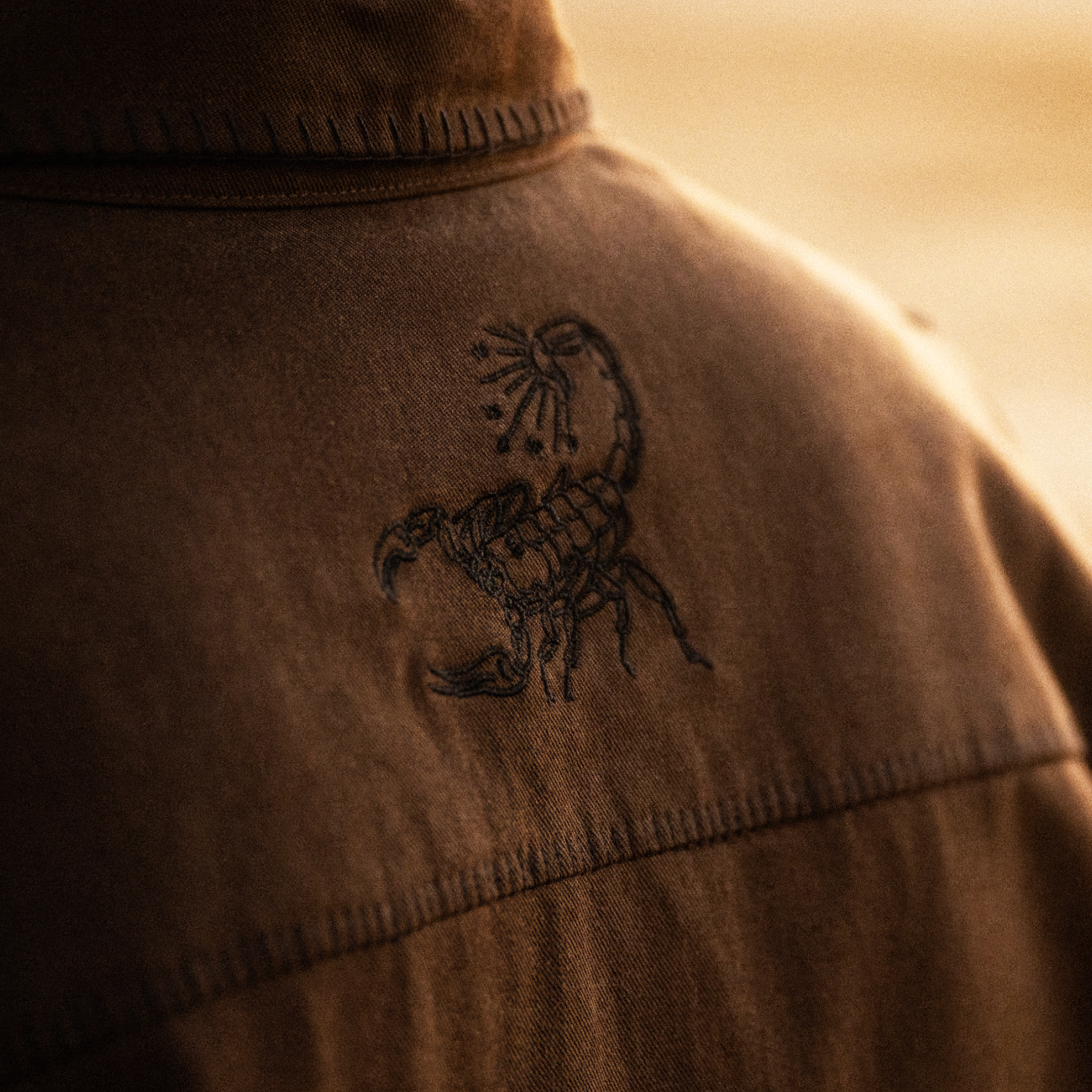 Brown button-up shirt with black scorpion embroidery design on the chest and ribbed collar detail
